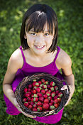拿着一篮子刚摘的草莓的女孩。
