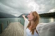 欢呼的年轻女子在湖边的码头上张开双臂