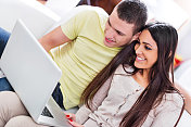 年轻夫妇微笑着使用电脑。