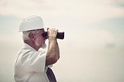 高级商人用双筒望远镜在海港视察工作