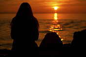 坐在岩石上迎着日出的女人