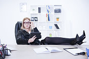 三十多岁的女商人拿着平板电脑坐在办公桌前