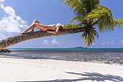 一个女人在海滩上的棕榈树上休息。