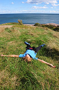 快乐的男孩躺在海边的草地上