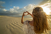 年轻女子把海滩风景画成心形