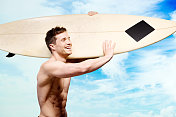 赤裸上身的肌肉冲浪者持有冲浪板