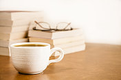 书和老花镜堆在一起，咖啡在马克杯里。