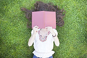 年轻的波西米亚女人躲在一本书后面
