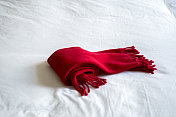 白色的床上围着红色的羊毛围巾