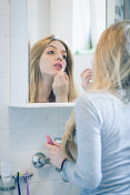 美丽的金发女孩，早晨的头发和嘴唇在浴室的镜子前固定