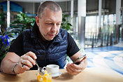 一个成熟的男人一边拿着咖啡一边看手机