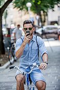 年轻时尚帅哥骑自行车和使用智能手机的肖像