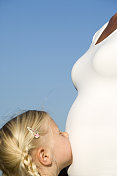 年轻的女孩抚摸着她怀孕的母亲的肚子